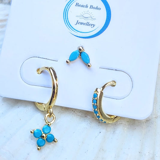 Gold hoop earrings with blue stones on a branded jewelry card.
