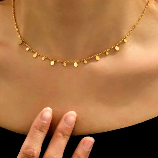 Gold necklace on a person's neck with a hand touching the skin