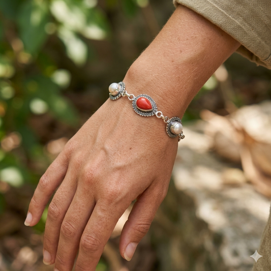 Bracelet with red stone and pearls on a wrist against a natural background
