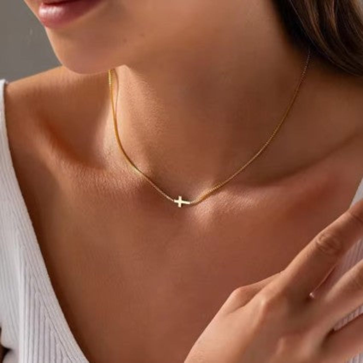 Gold necklace with a cross pendant worn by a person