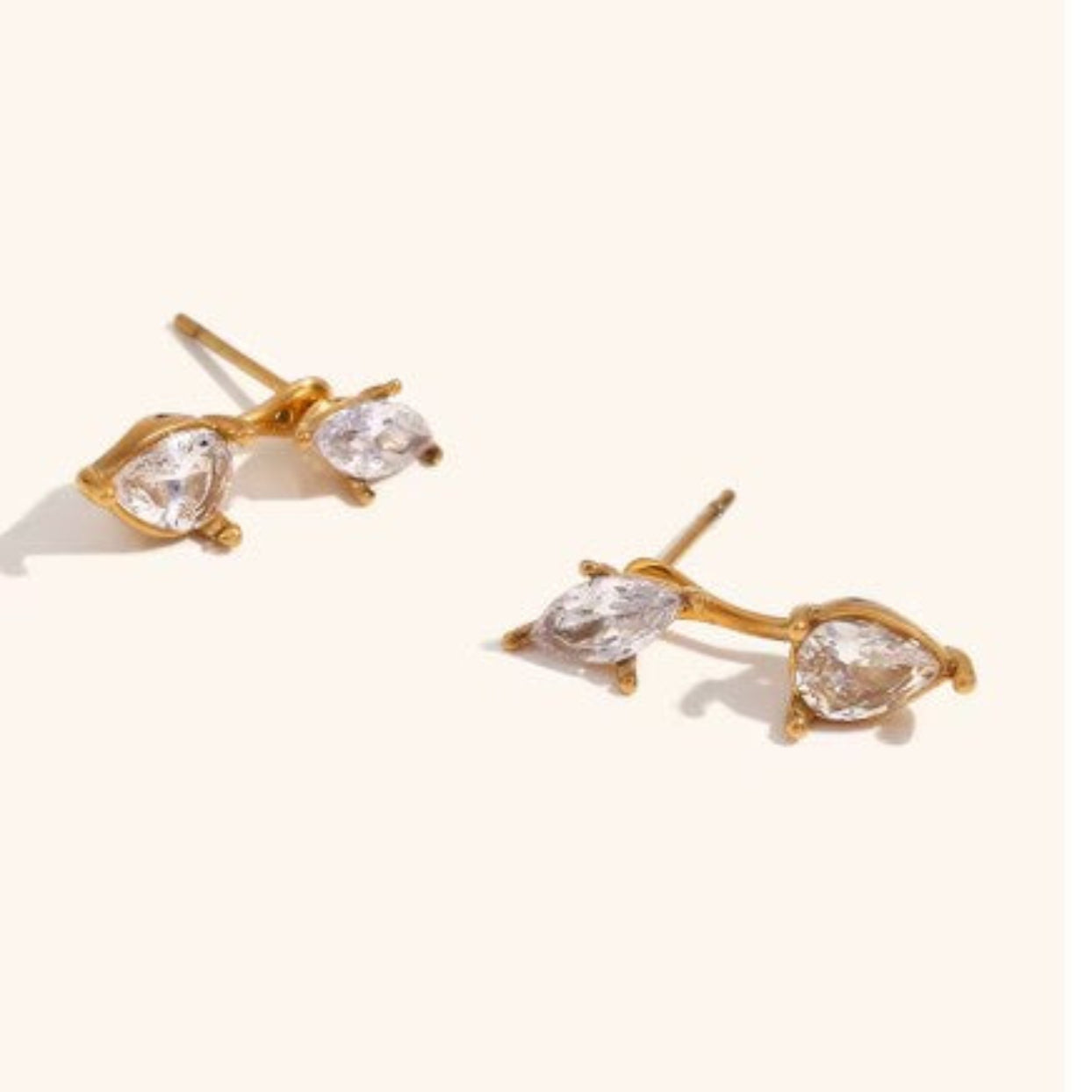 Gold earrings with clear gemstones on a light background