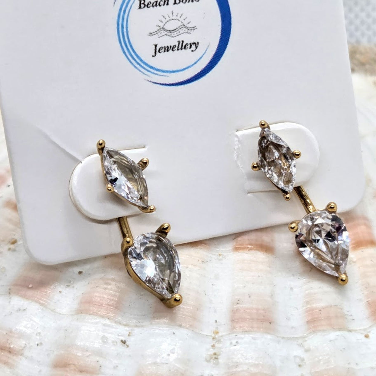 Pair of gold and crystal earrings on a white card with 'Beach Bond Jewellery' branding.