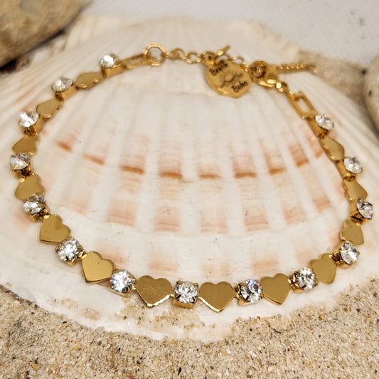 Gold bracelet with heart-shaped charms on a seashell