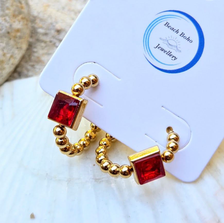 Gold beaded hoop earrings with square red gemstone accents, displayed on a white Beach Boho Jewellery card.