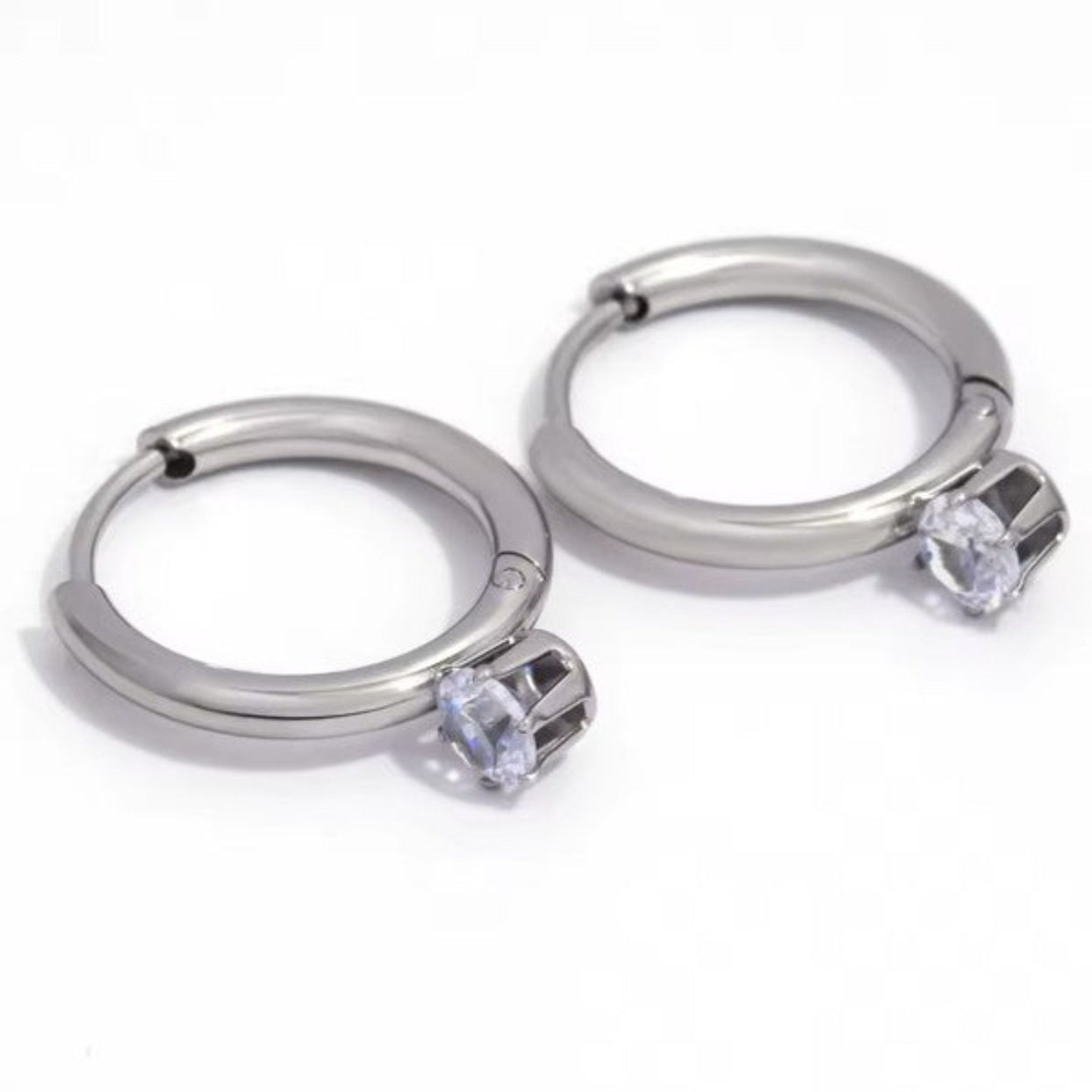 Pair of silver hoop earrings with clear gemstones on a white background