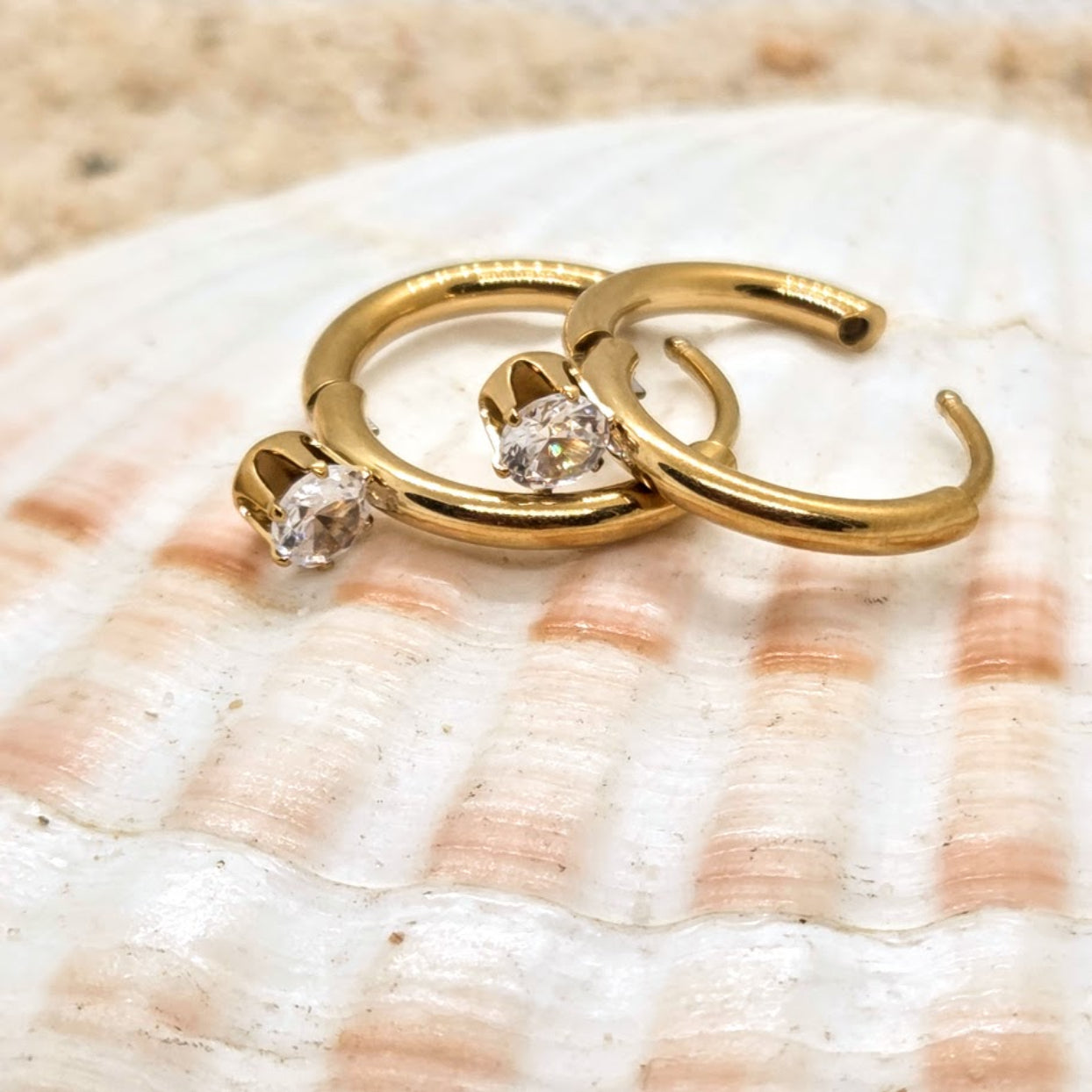 Gold hoop earrings with diamonds on a seashell