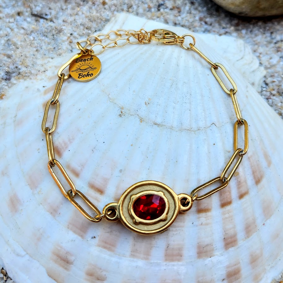 Gold bracelet with a red gemstone on a seashell