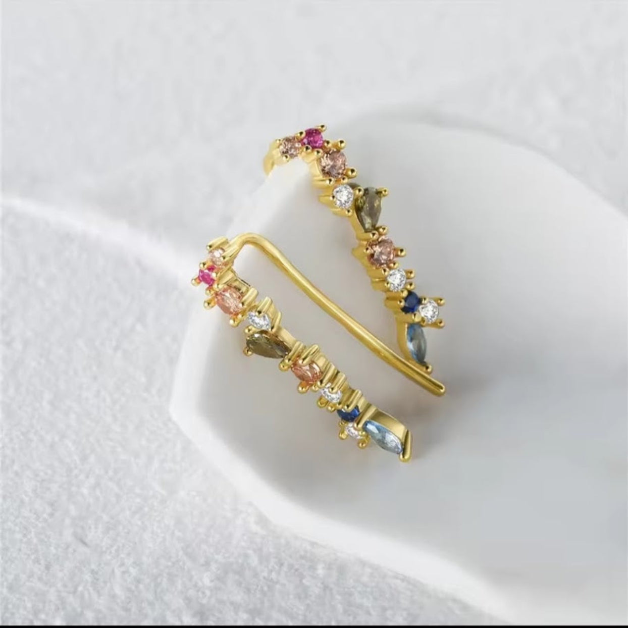 Gold earrings with multicolored gemstones on a white background