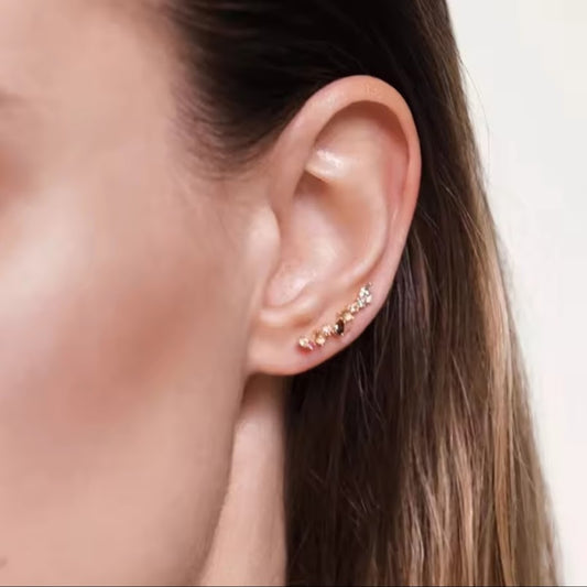 Close-up of an ear wearing a small earring with a neutral background