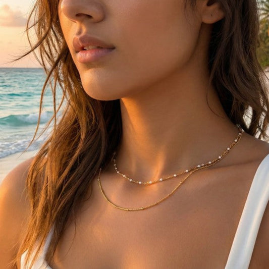 Woman wearing a gold necklace with a beach in the background