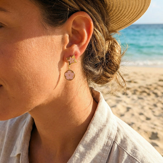 Close-up of a person wearing earrings with a beach in the background