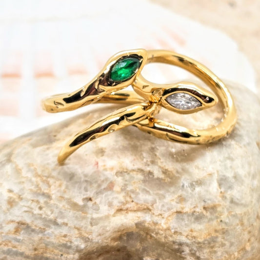 Gold ring with green gemstone on a stone surface