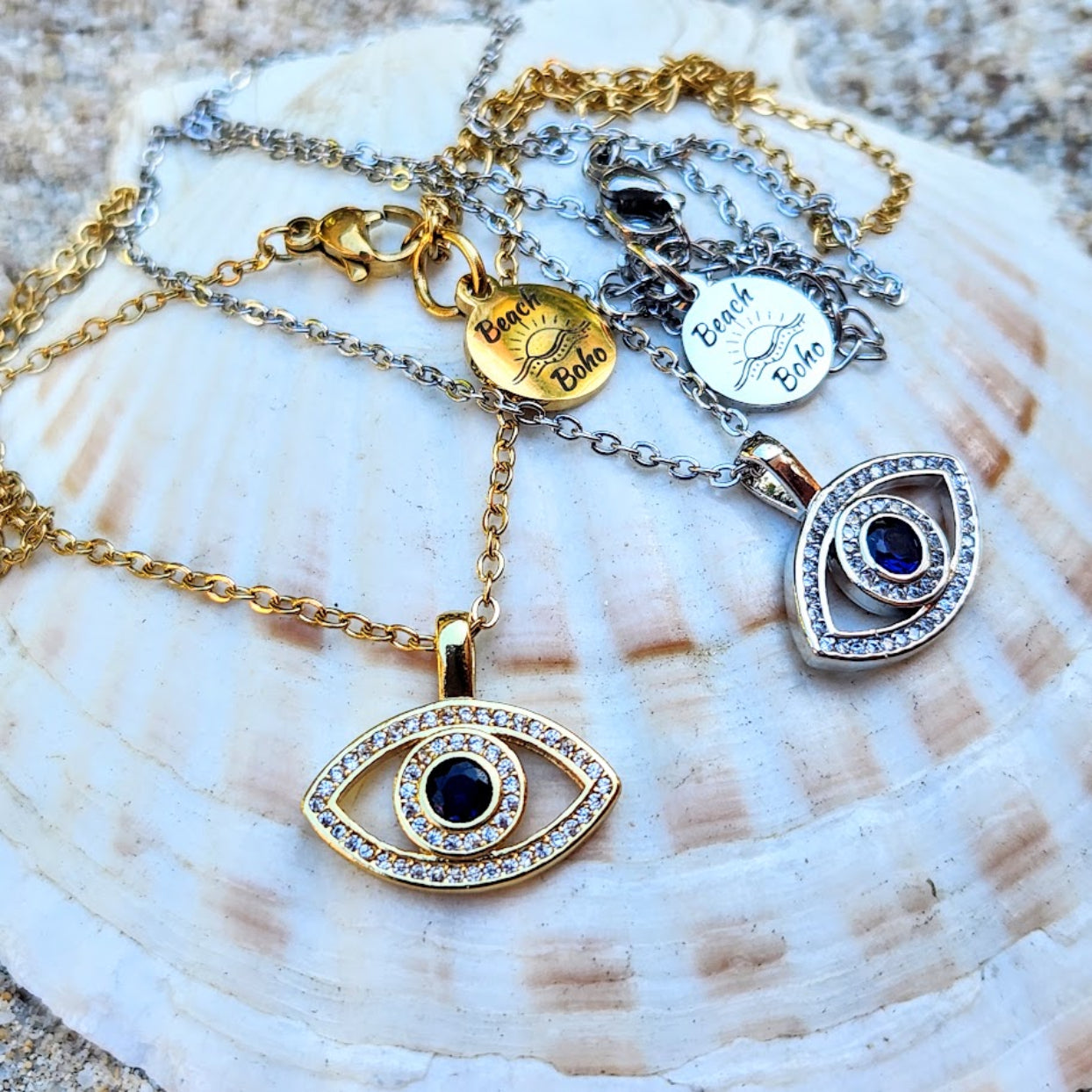 Gold and silver necklaces with eye-shaped pendants on a shell background