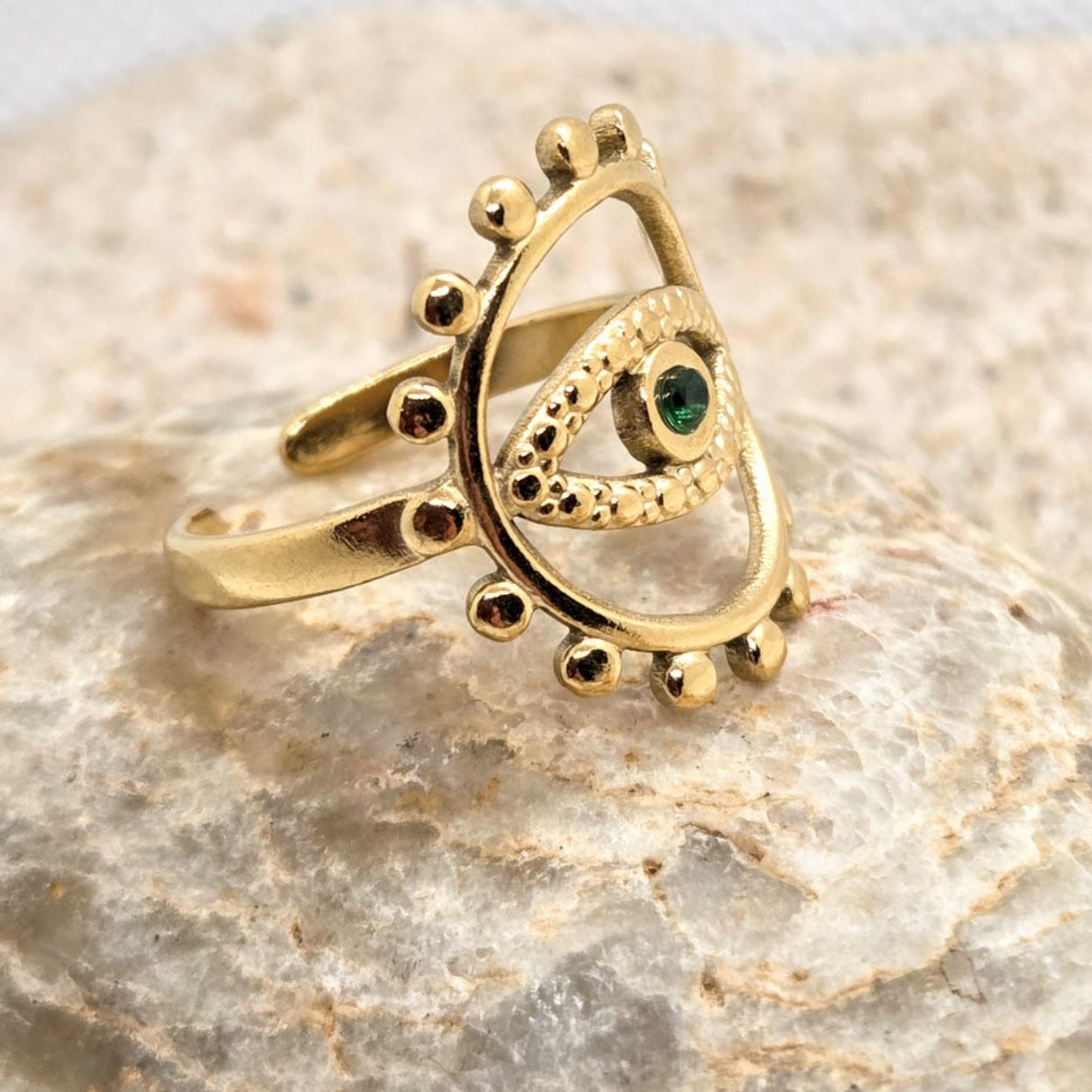 Gold ring with a green gemstone on a stone surface