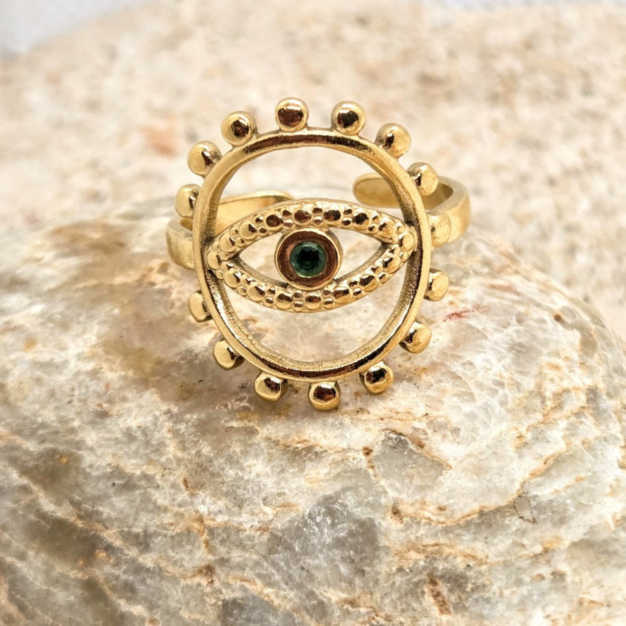 Gold ring with eye design on a stone surface
