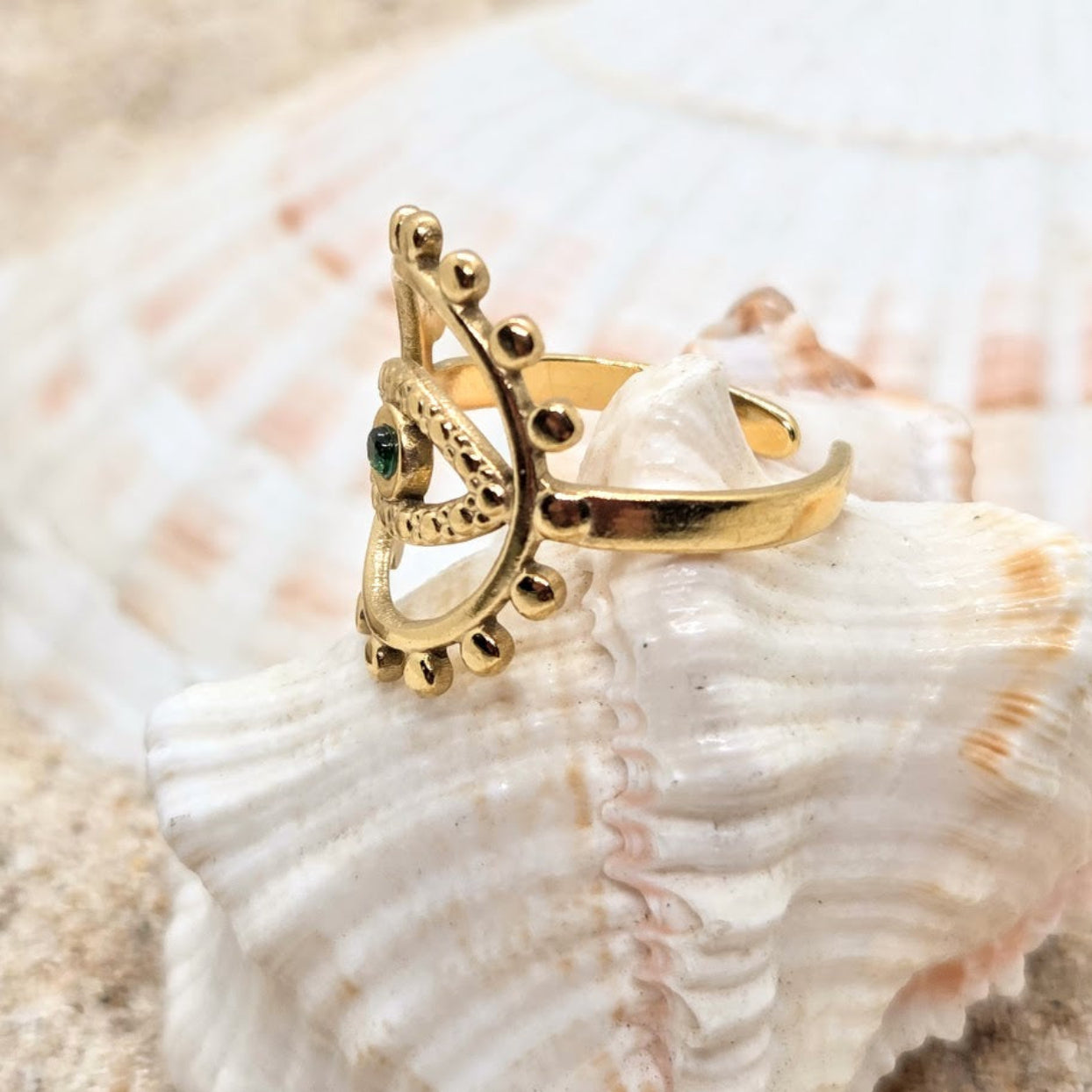 Gold ring with a green gemstone on a seashell