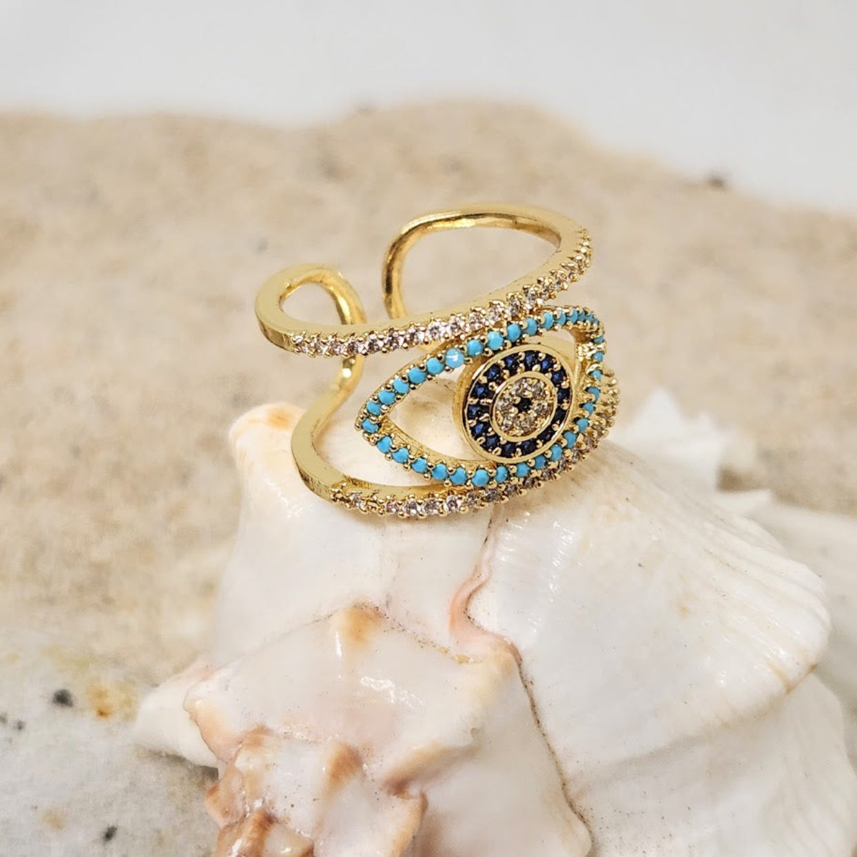 Gold ring with blue and black gemstones on a shell