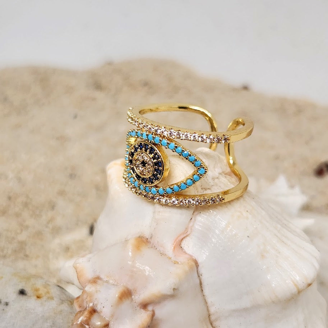 Gold ring with blue and black gemstones on a shell