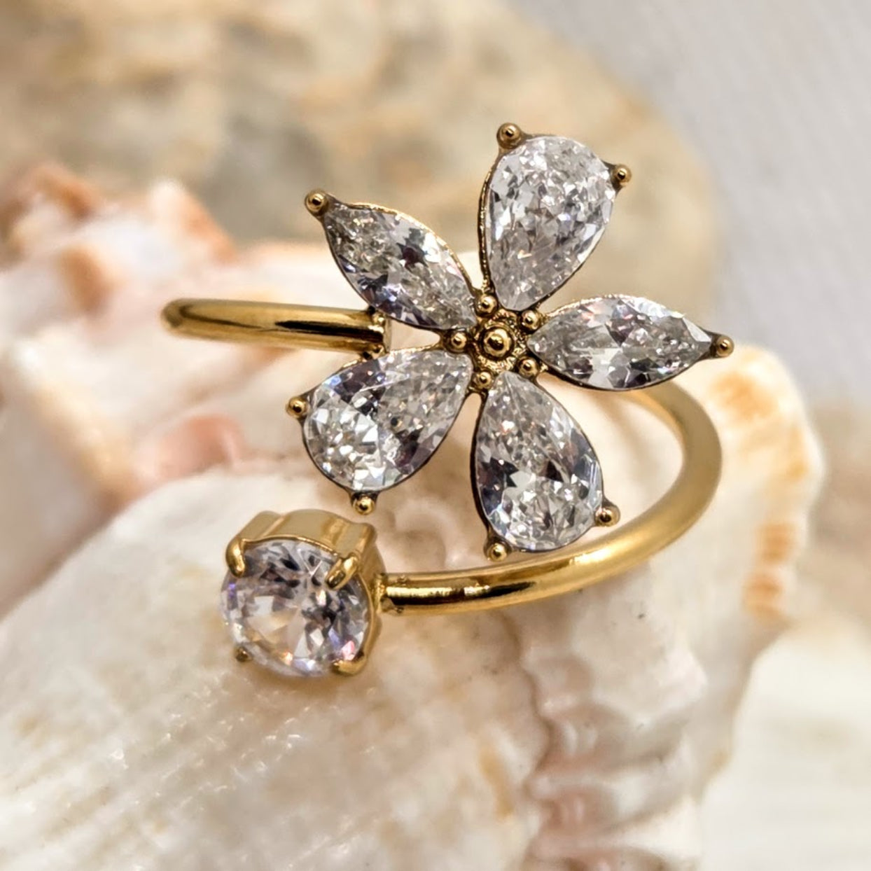 Gold ring with diamond-shaped gemstones on a shell background