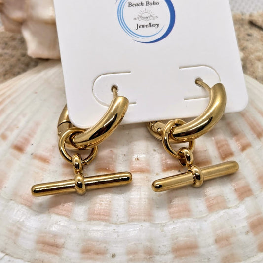 Gold earrings on a shell with 'Beach Boho Jewellery' card in the background