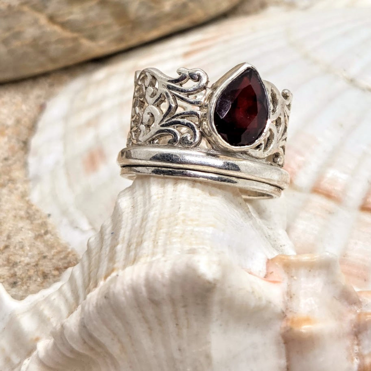 Silver ring with a garnet stone on a seashell