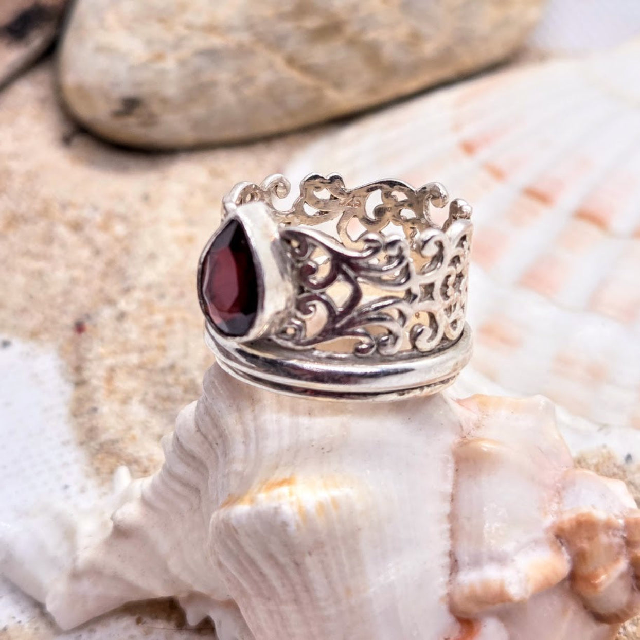 Silver ring with a red gemstone on a seashell
