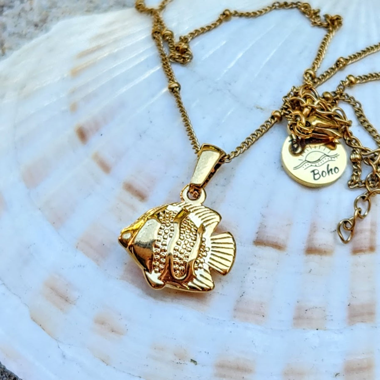 Gold fish pendant necklace on a shell background