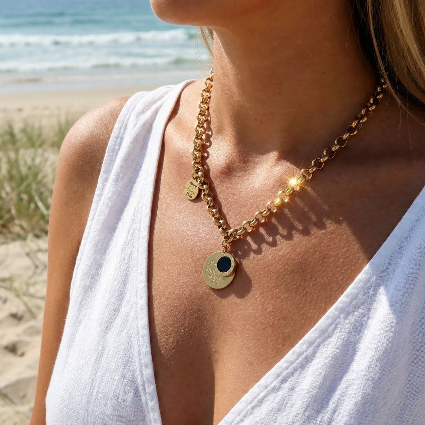 Woman wearing a gold necklace with a beach in the background