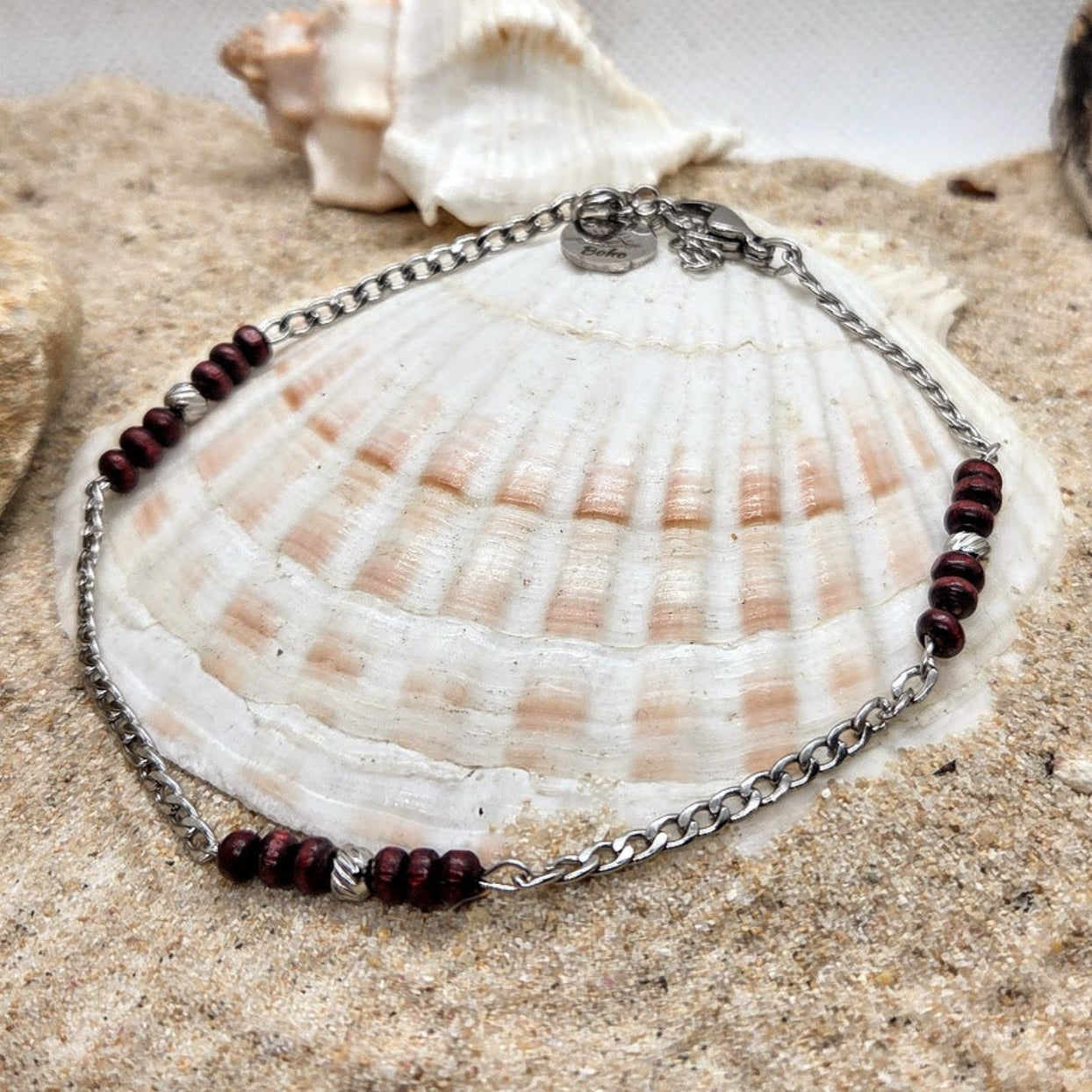 Bracelet with brown beads on a shell and sand background