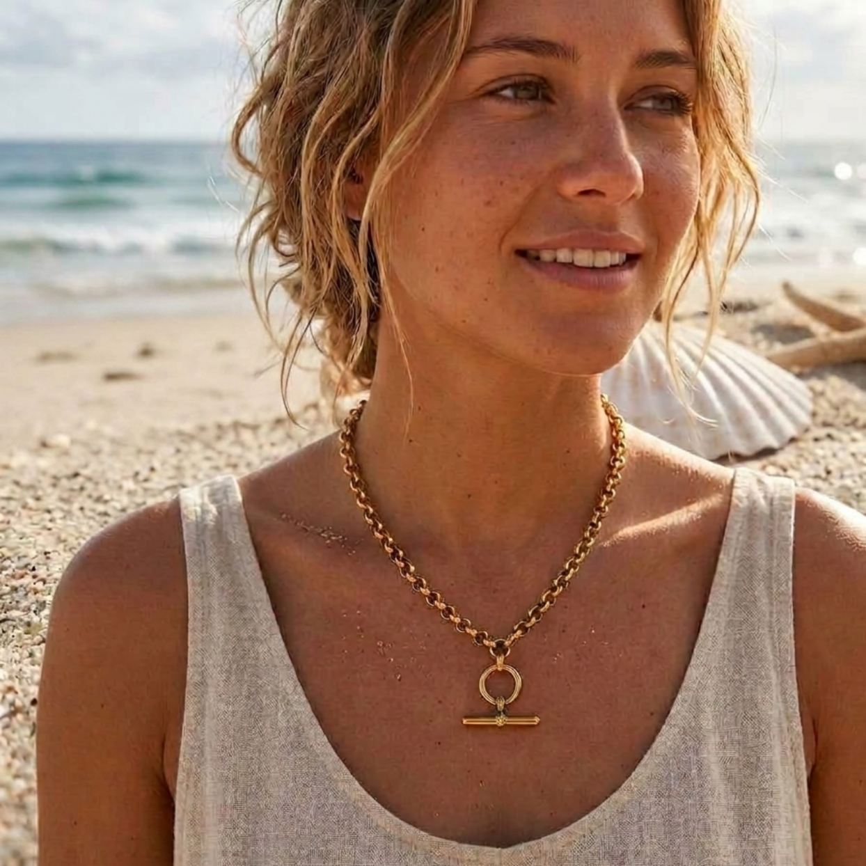 Woman on a beach wearing a gold necklace with a pendant