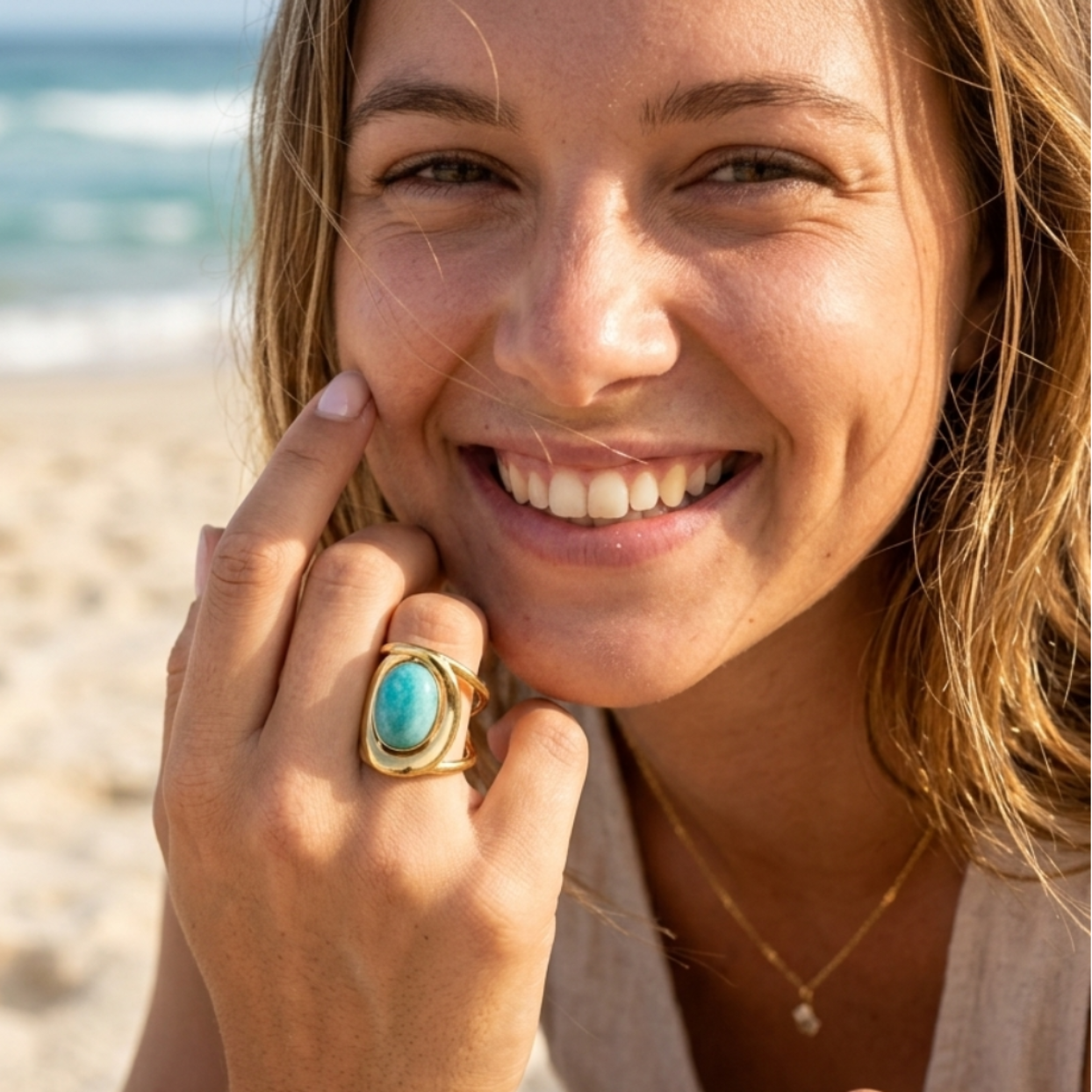 Woman on a beach wearing a turquoise ring, holding a shell.