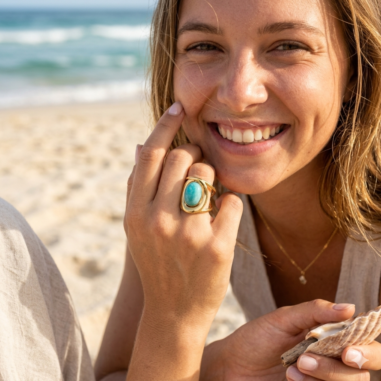 Woman on a beach wearing a turquoise ring, holding a shell.