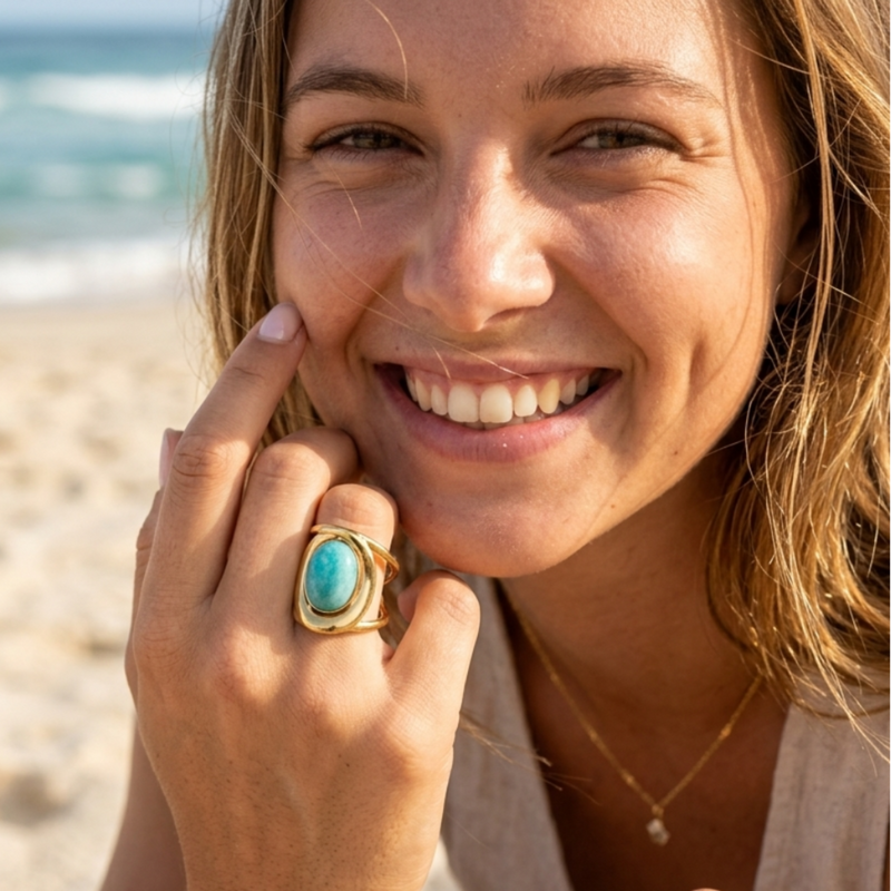 Woman on beach wearing waterproof gold ring with turquoise stone
