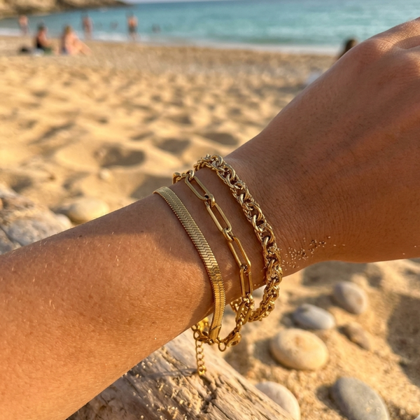 18k gold waterproof bracelet bundle stacked on wrist at the beach