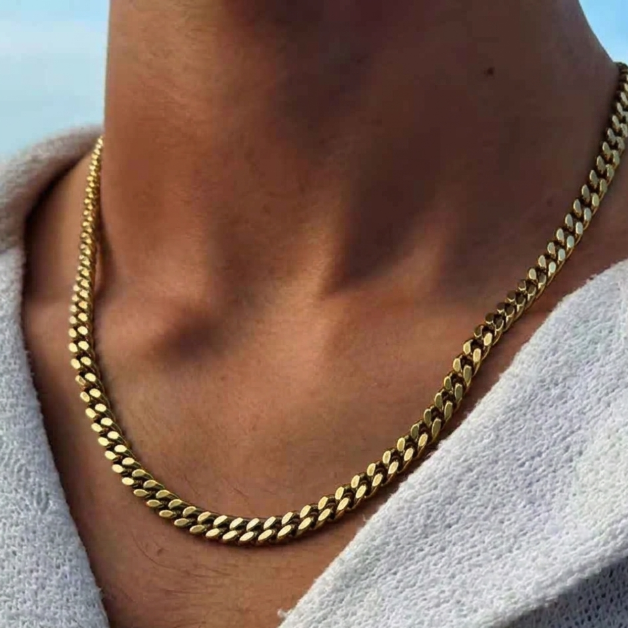 Gold chain necklace worn by a person with a blurred background