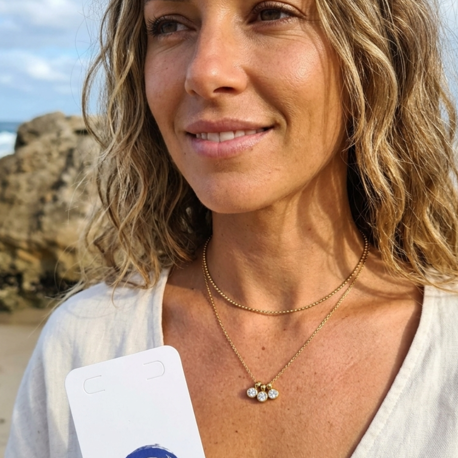 Woman holding a product on a beach with ocean and rocks in the background