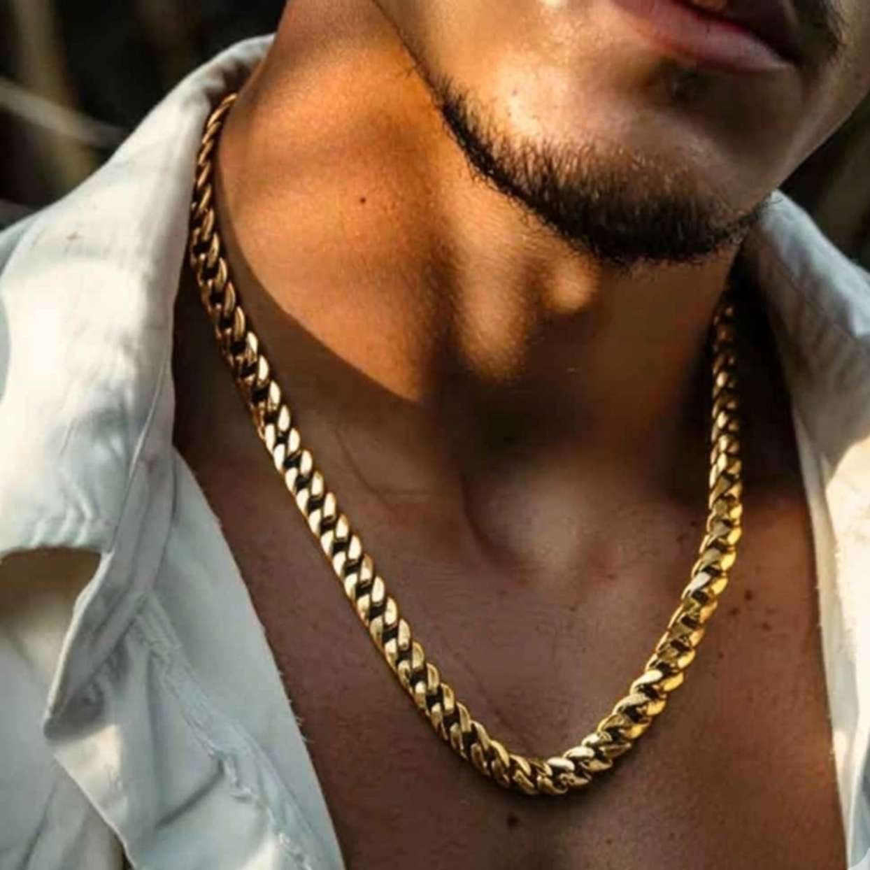 Man wearing a gold chain necklace with a blurred background