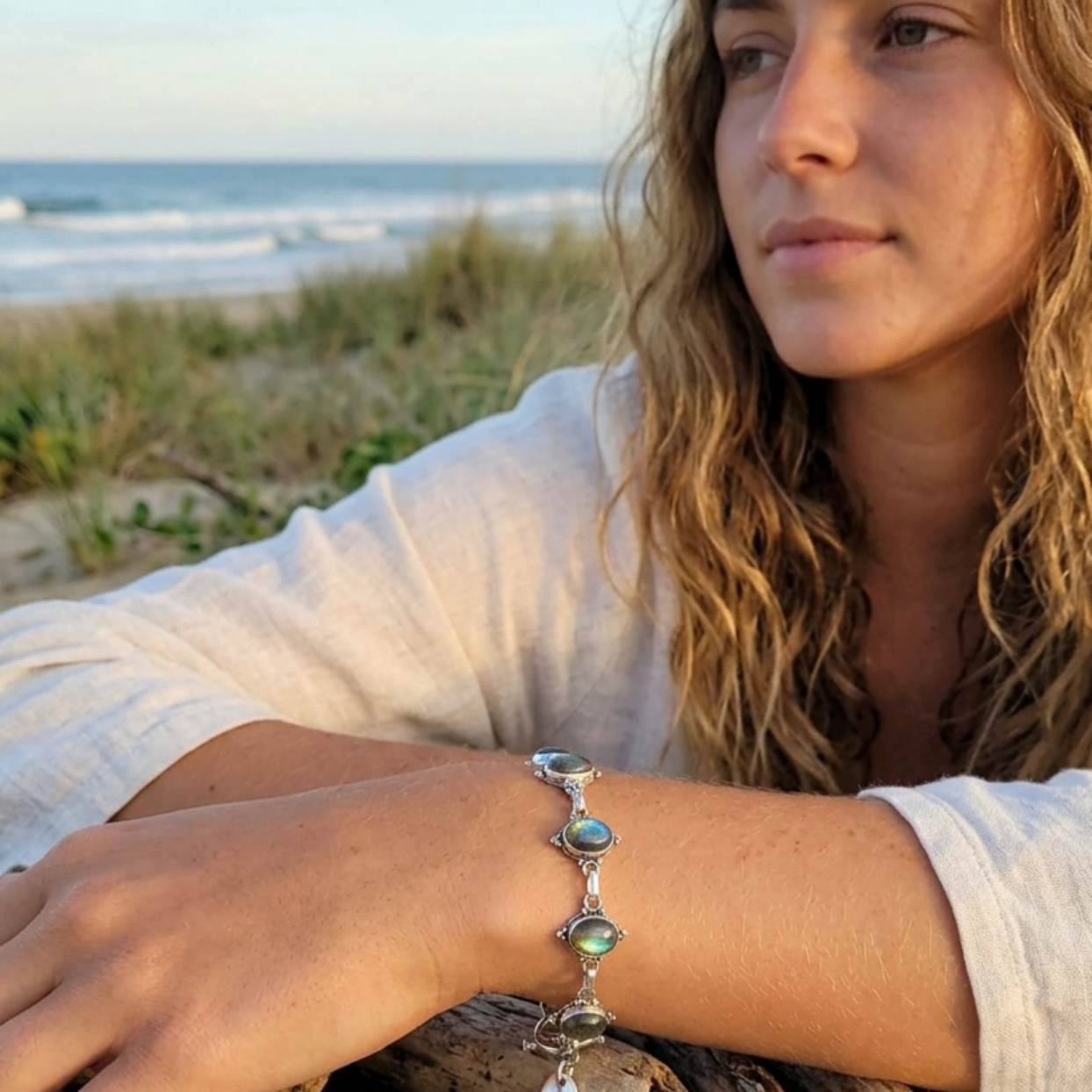 Woman on a beach wearing a silver bracelet with gemstones