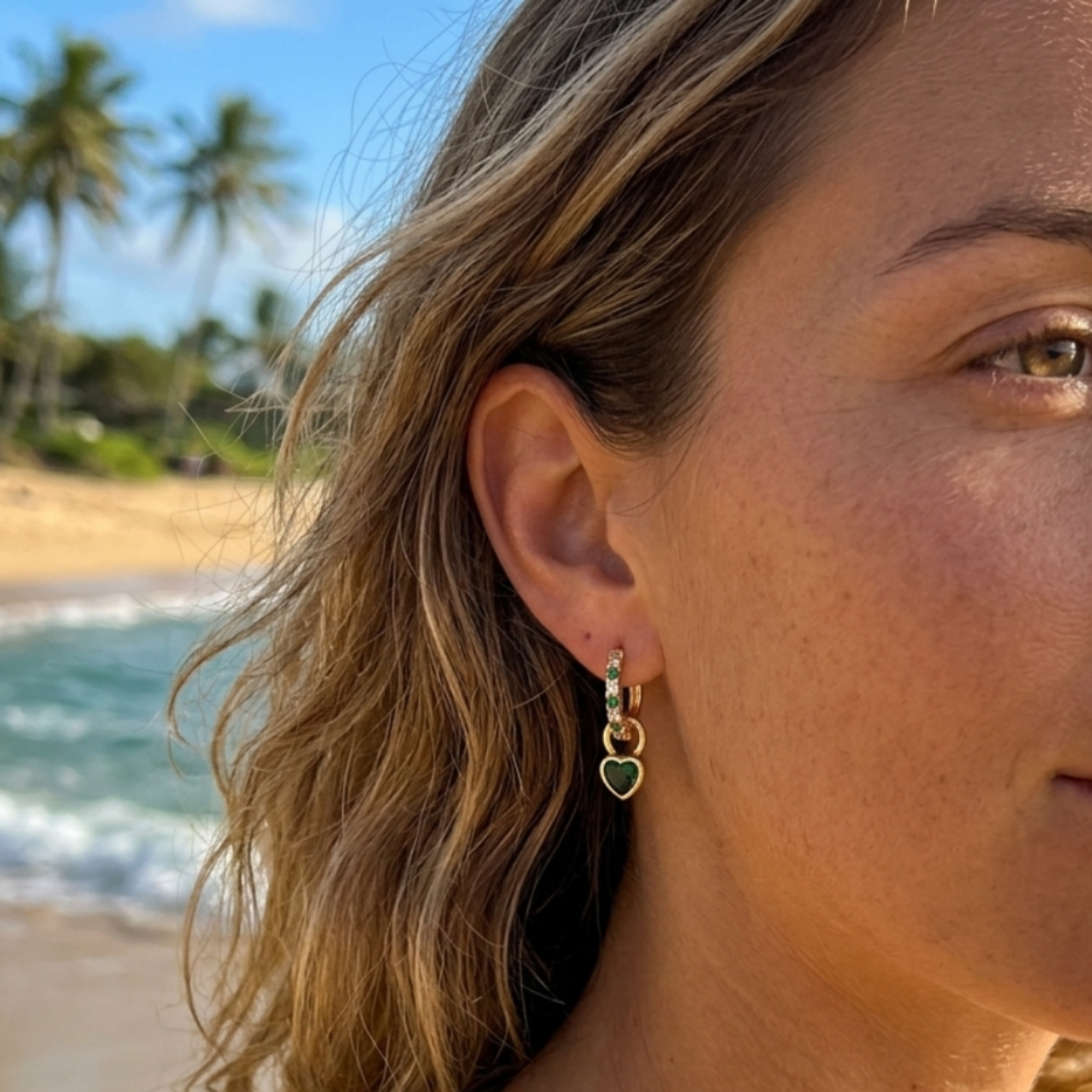 Woman with earrings on a beach with palm trees and ocean in the background