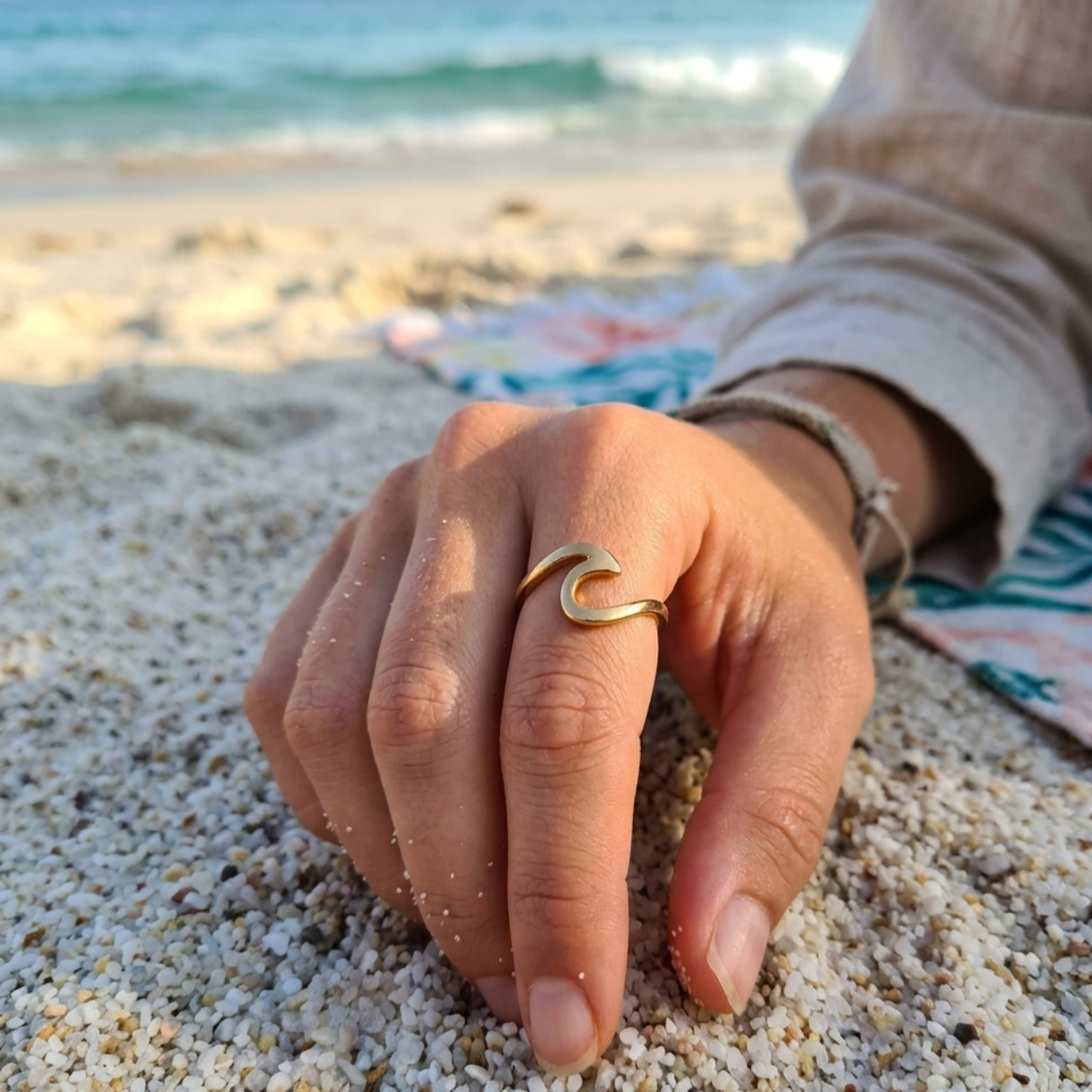 Hand with a gold ring on a sandy beach
