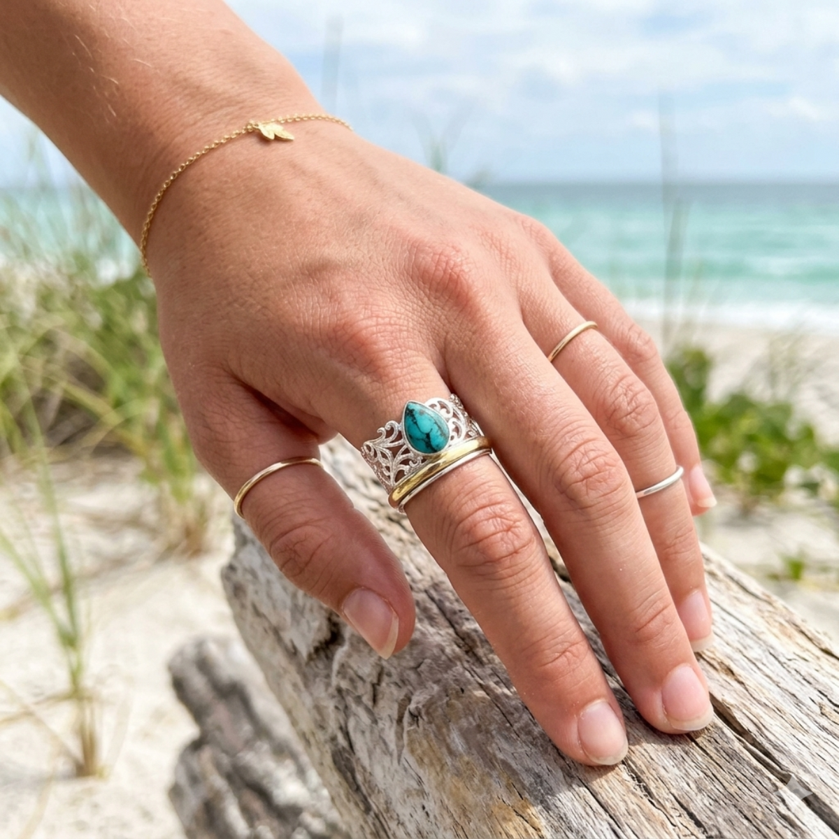 Hand with multiple rings on a beach setting