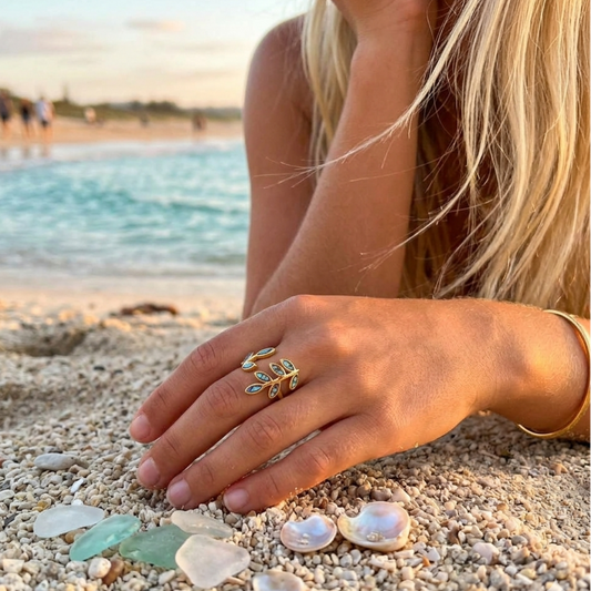 Hand with a ring on a beach with seashells