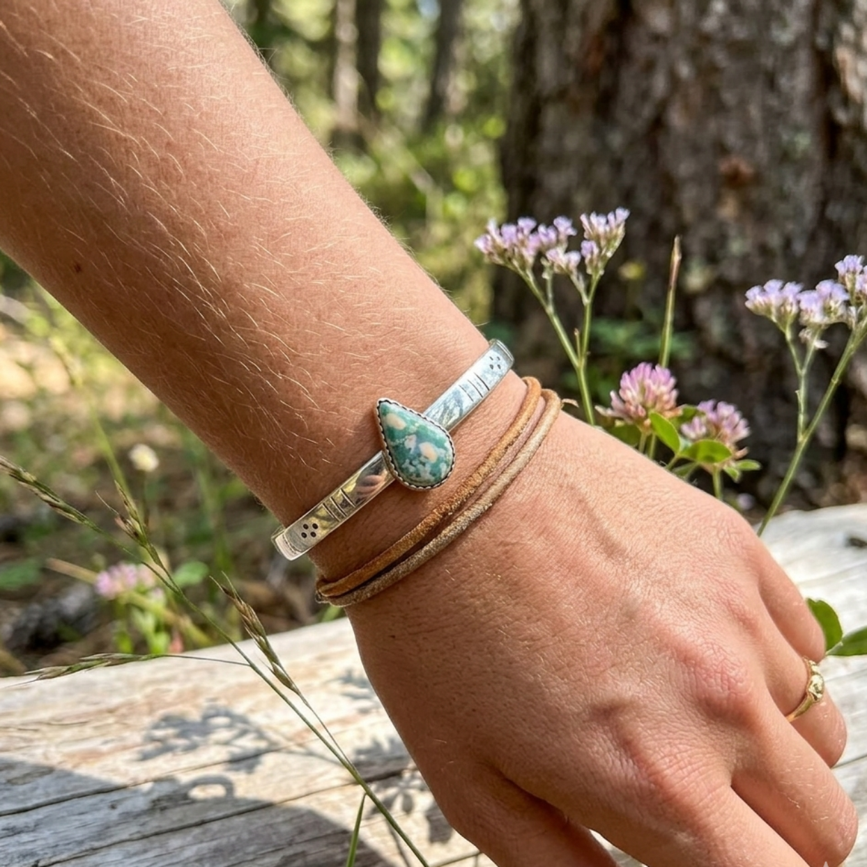 Hand wearing a bracelet with a natural background of plants and wood