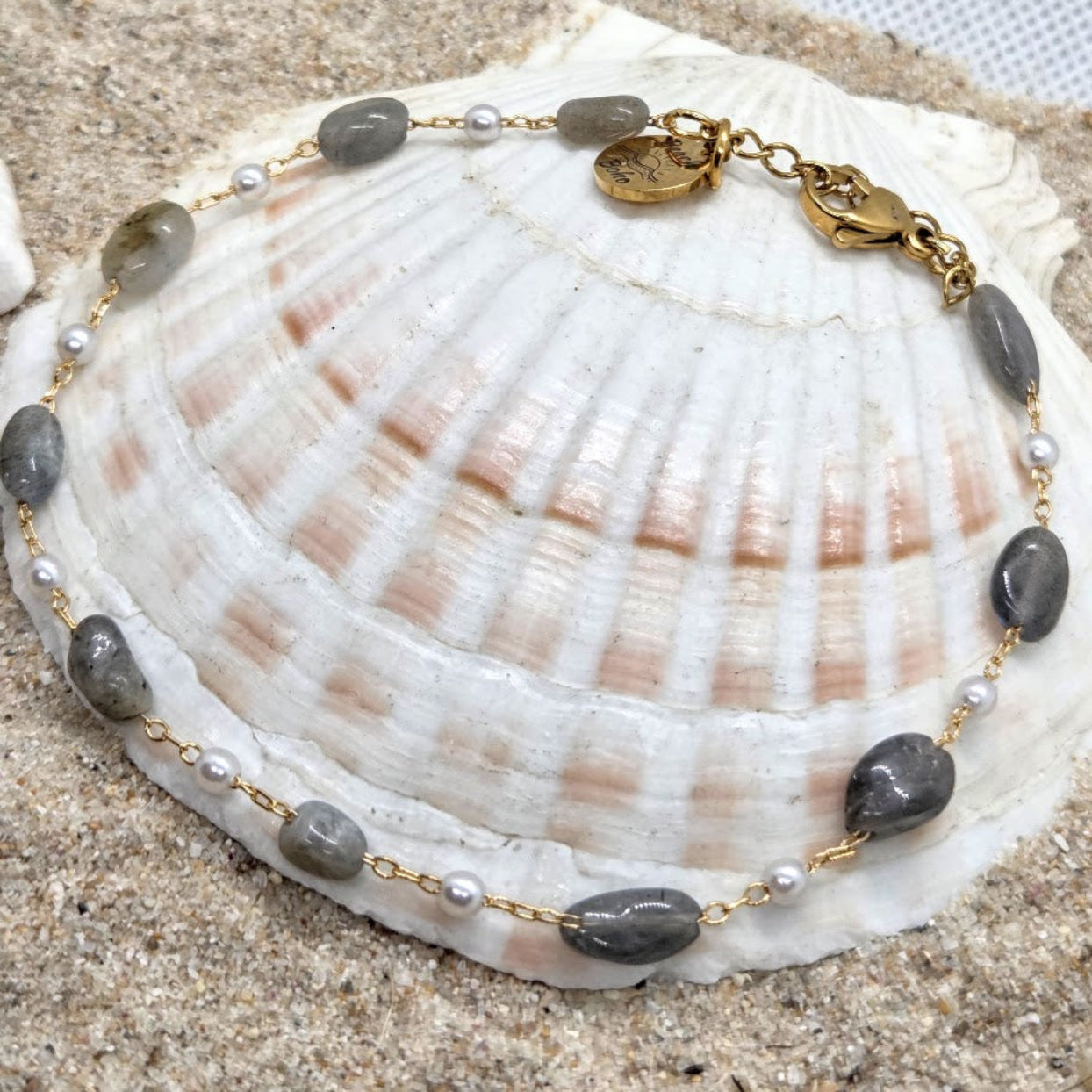 Necklace with gray stones and gold accents on a seashell