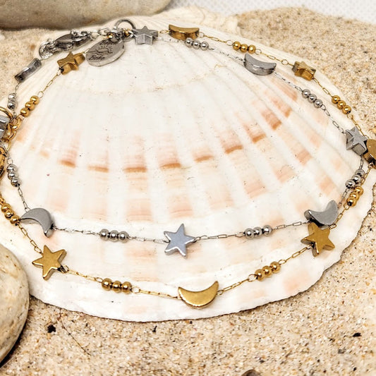 Necklace with star and moon charms on a seashell