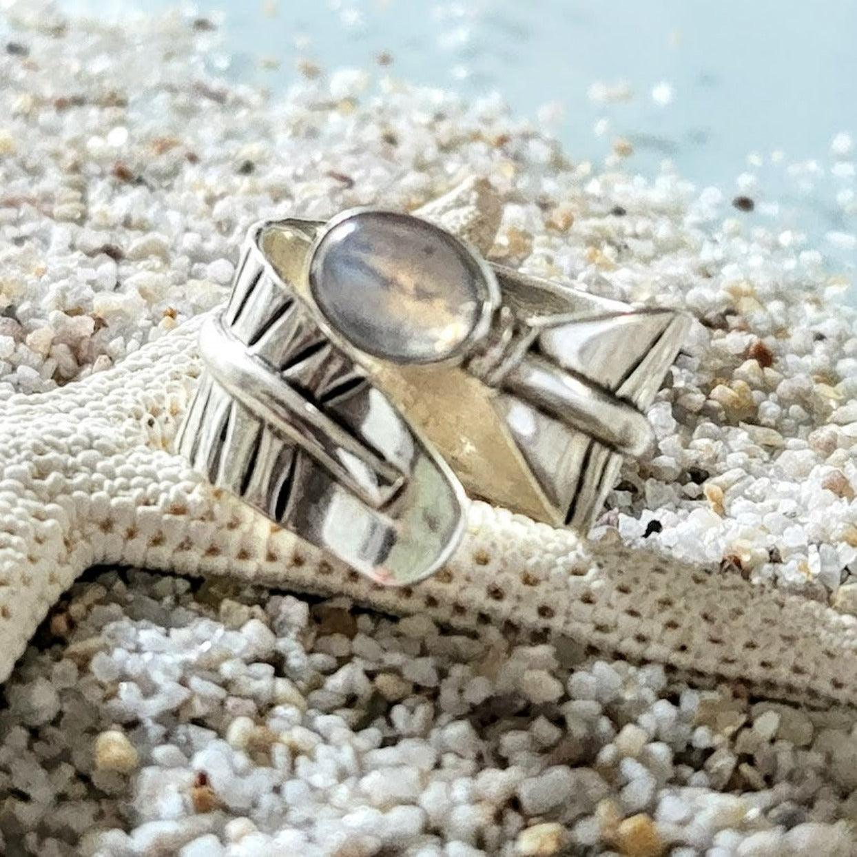 Silver ring with a stone on a starfish on sandy beach