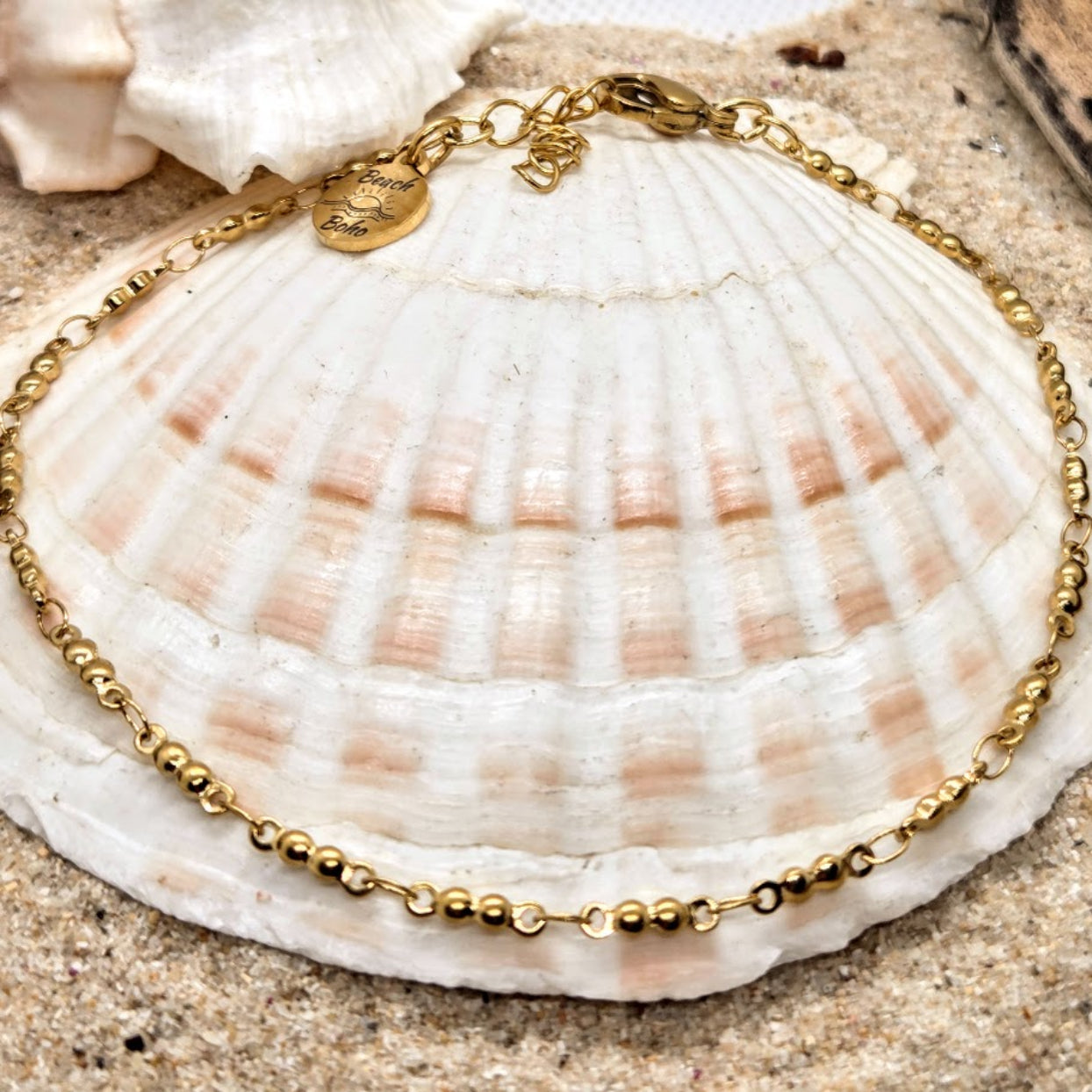 Gold bracelet on a seashell with sand background
