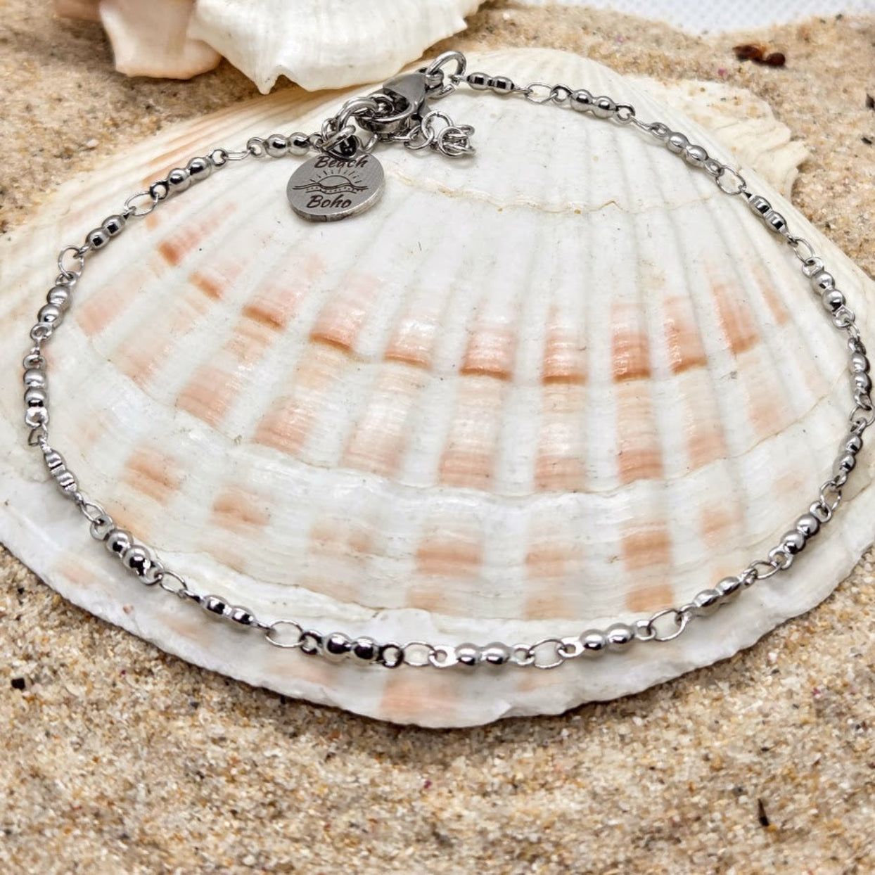 Silver bracelet with a heart-shaped charm on a seashell