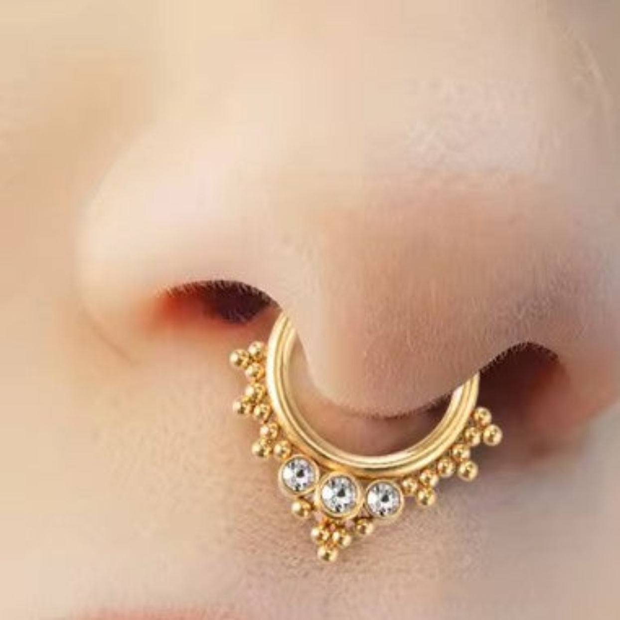 Gold hoop earring with crystal embellishments on a person's ear.