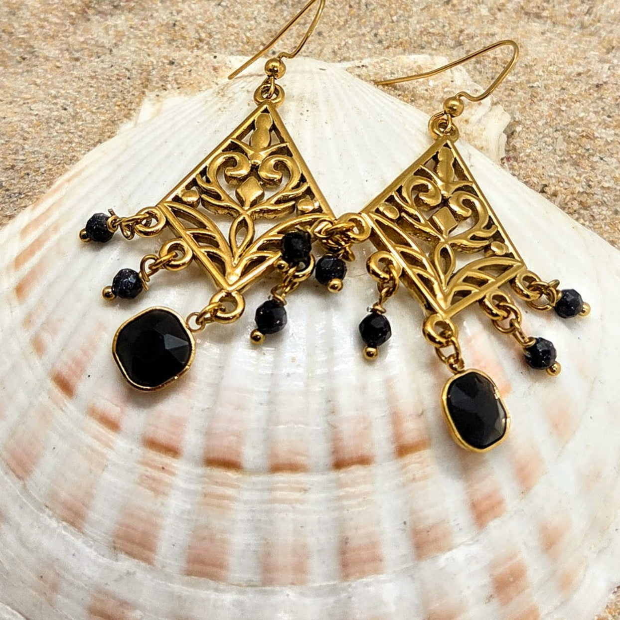 Gold earrings with black beads on a seashell